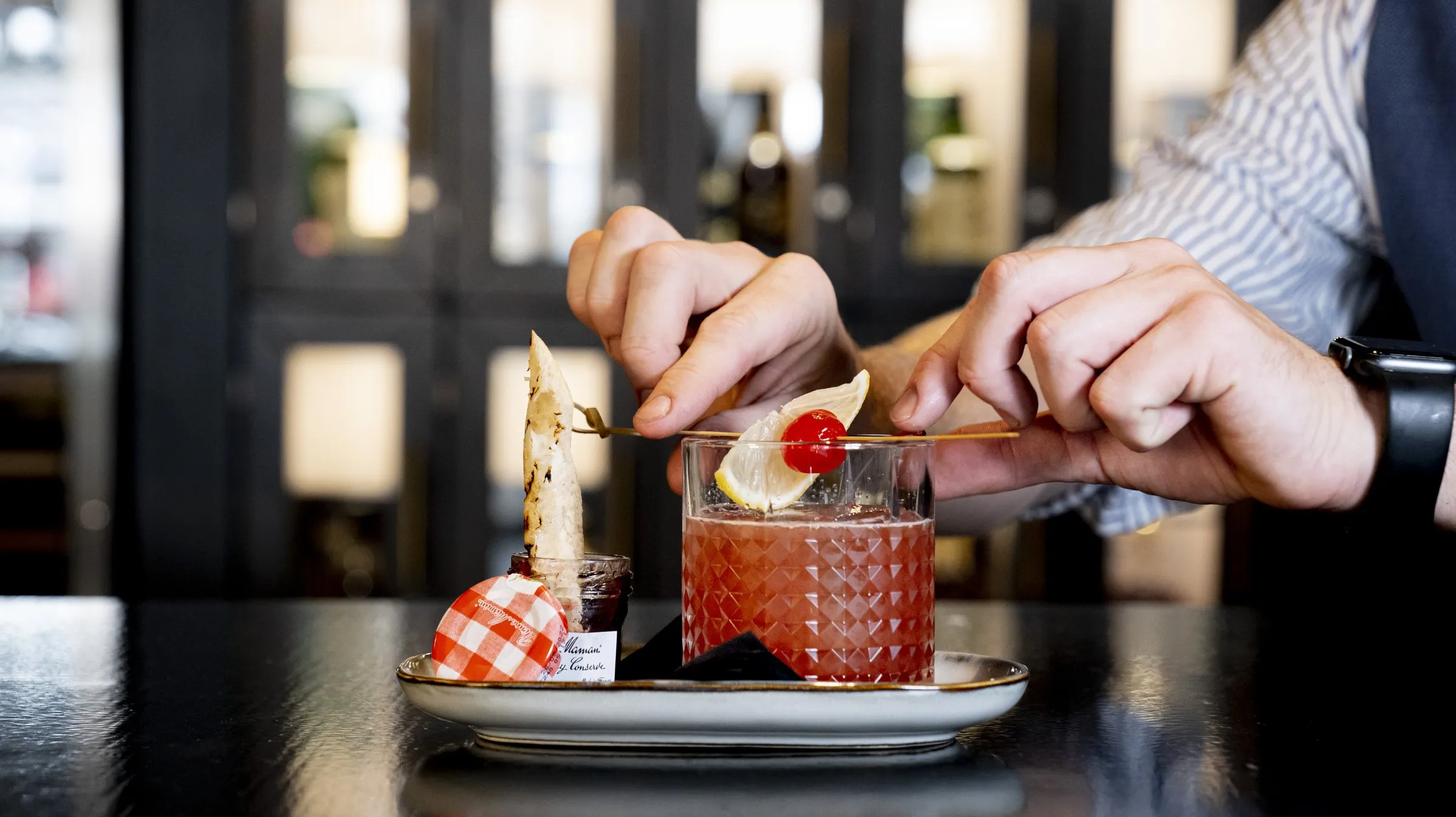 Hands finishing a plated dessert on a bar top